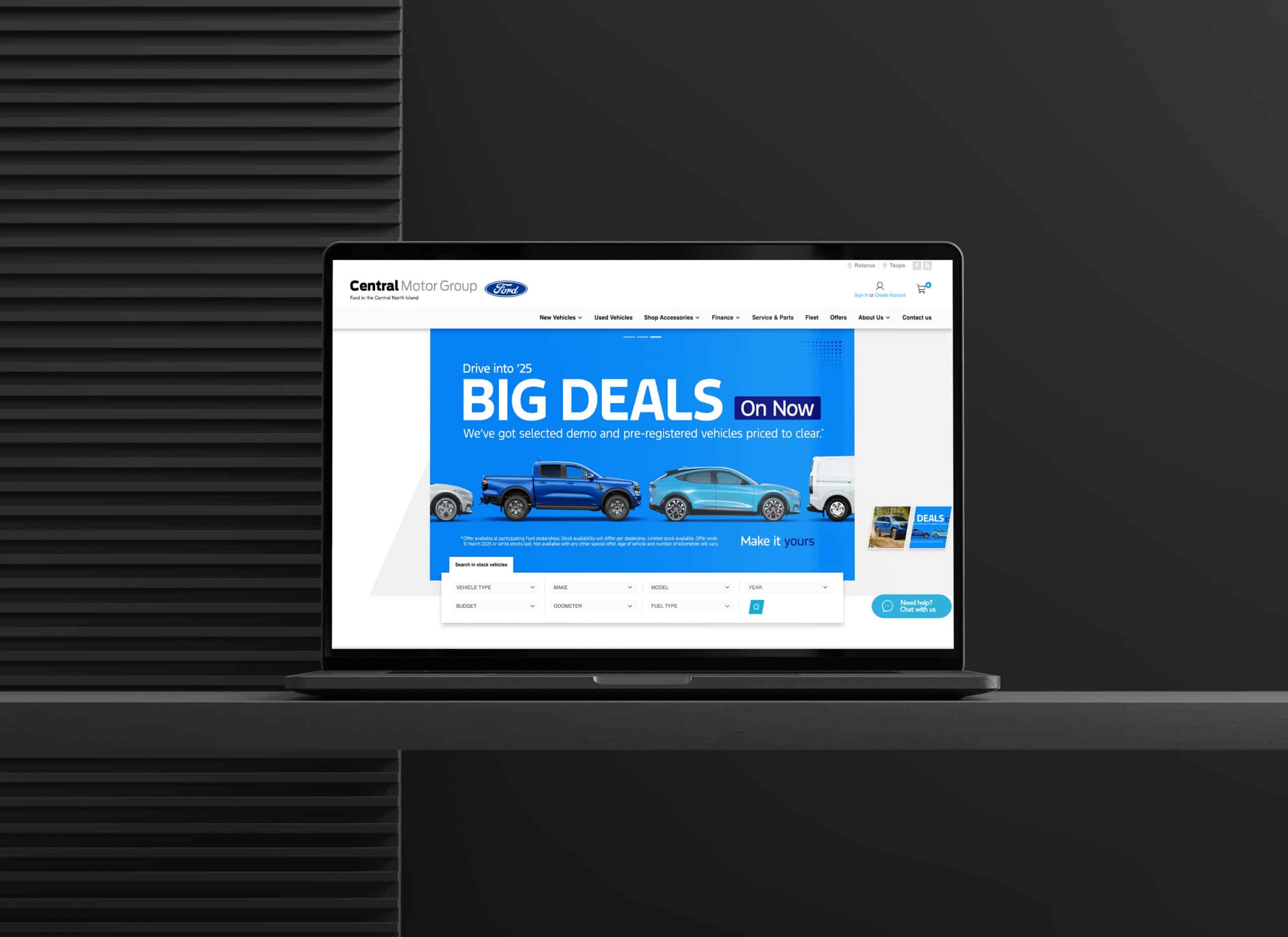 Laptop on a black desk displaying Central Motor Group’s website, featuring a bright blue promotional banner reading “BIG DEALS On Now” with images of Ford vehicles, set against a dark background.