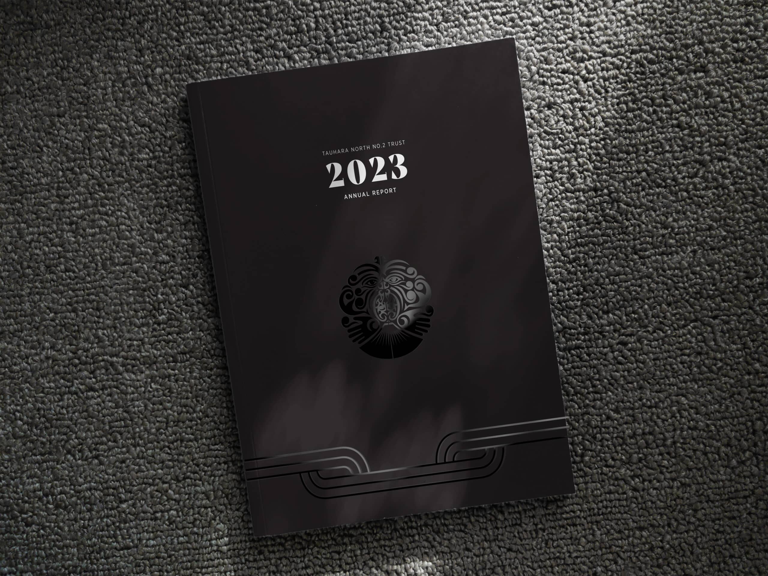 2023 Tauhara North No.2 Trust Annual Report with a sleek black cover featuring a silver embossed logo and modern line design, placed on a textured carpet background with soft light and shadow.